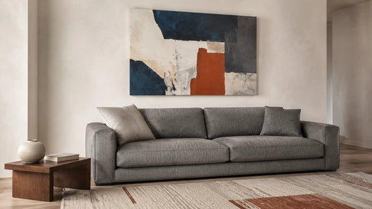 Medium-gray sofa beneath an original abstract canvas in bone, deep blue, muted rust and graphite